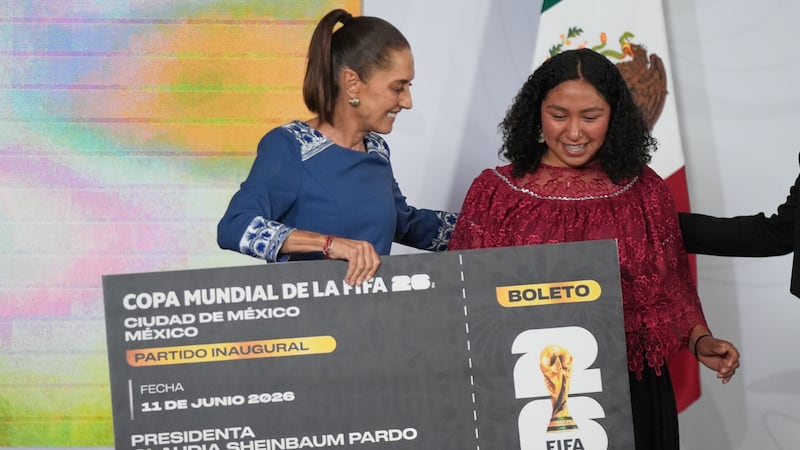 La presidenta mexicana Claudia Sheinbaum entrega un boleto simbólico para el partido inaugural...