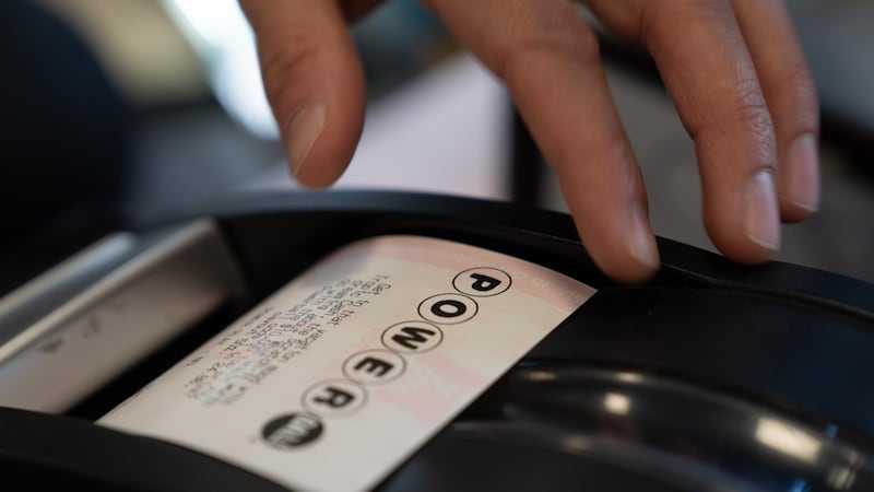 A convenience store employee grabs a Powerball lottery ticket for a customer on Monday, Dec....